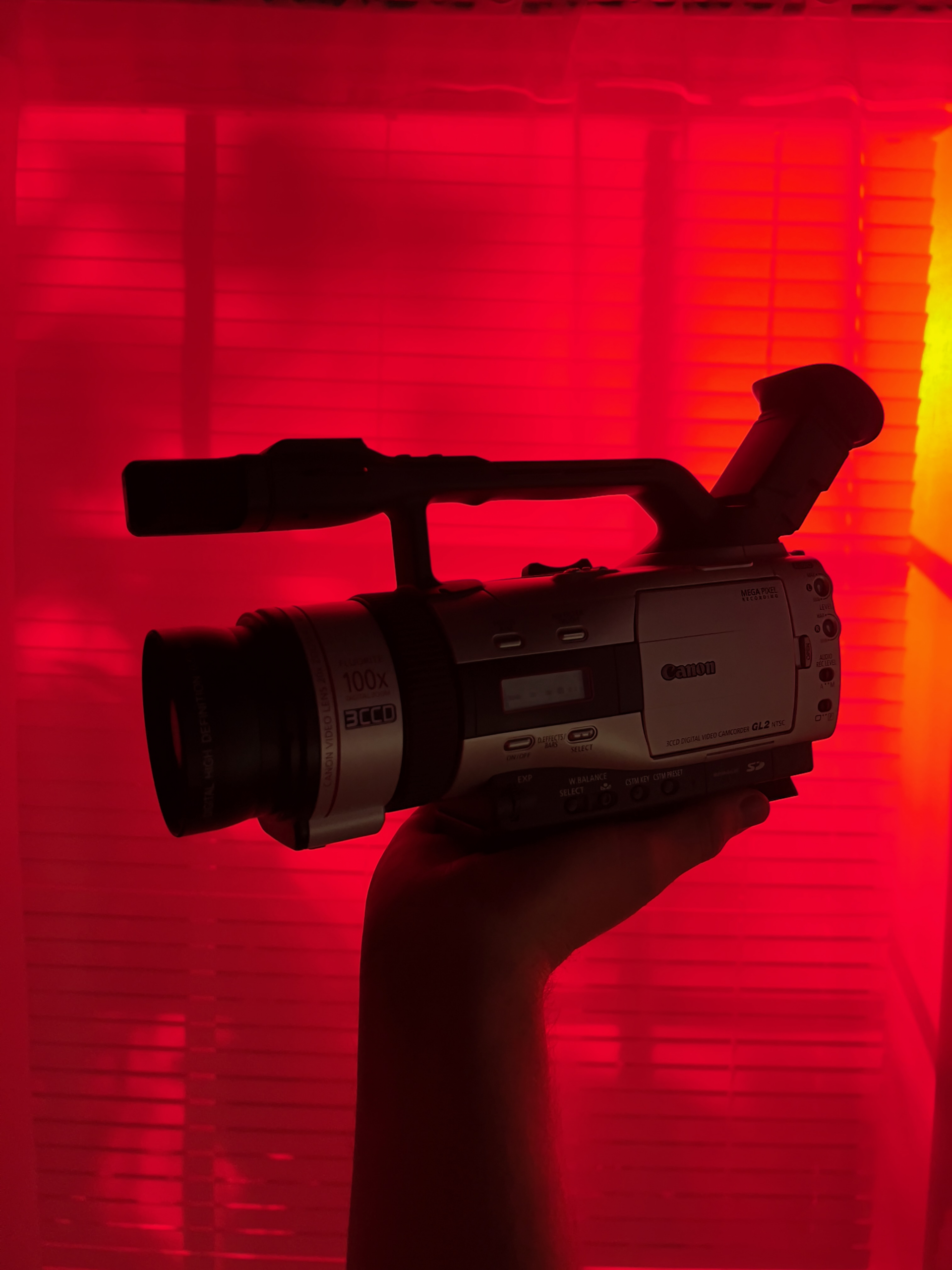 Canon GL2 held up against a curtain with red light